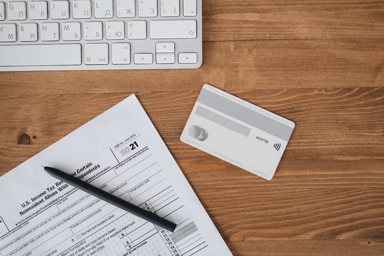 Overhead view of a desk with tax form, pen, keyboard, and contactless card.